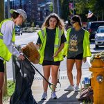 Students wearing neon vests clean up Hillsborough Street.
