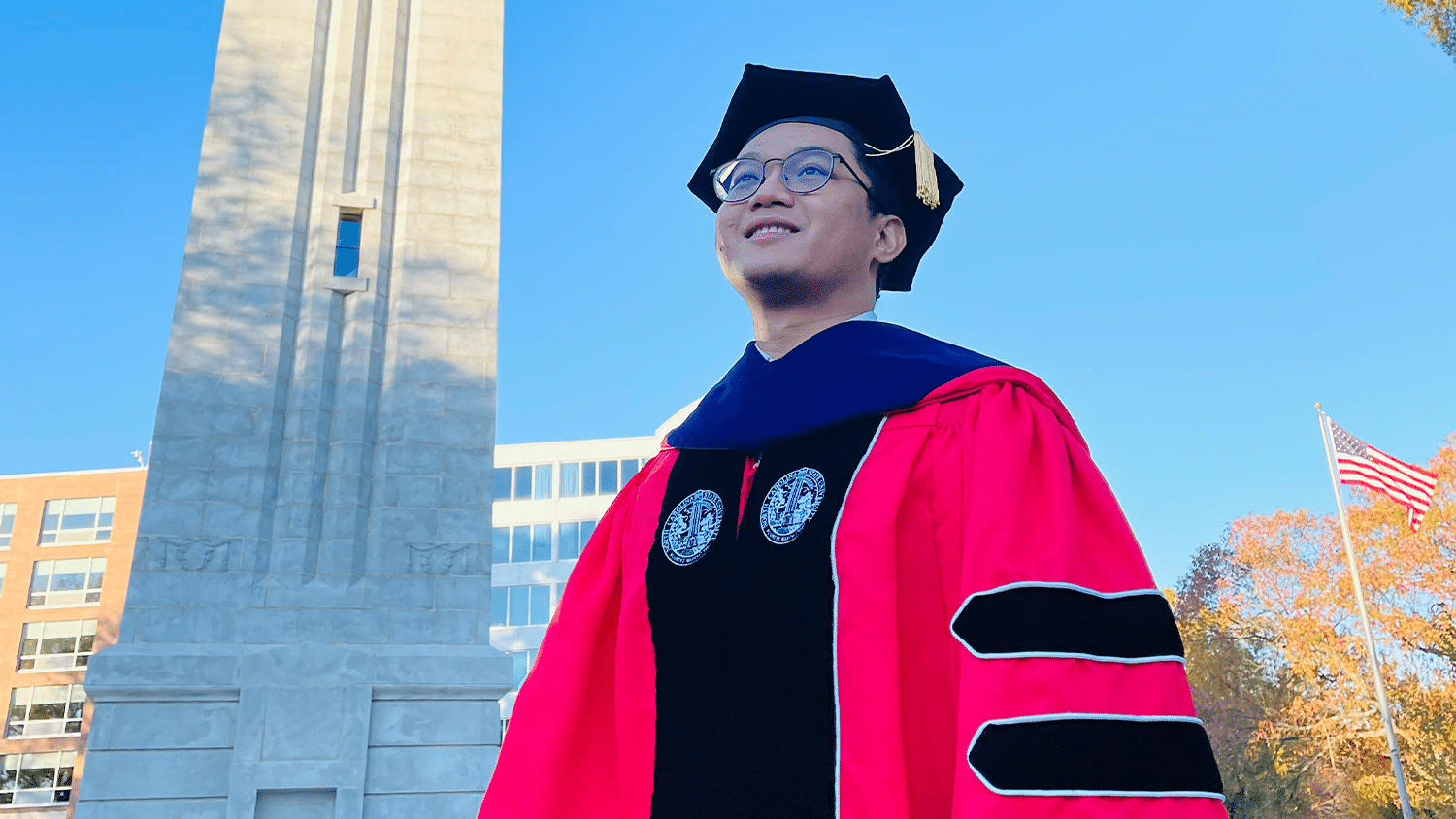 Arif Rachmatullah stands in front of the Belltower in his doctoral robe