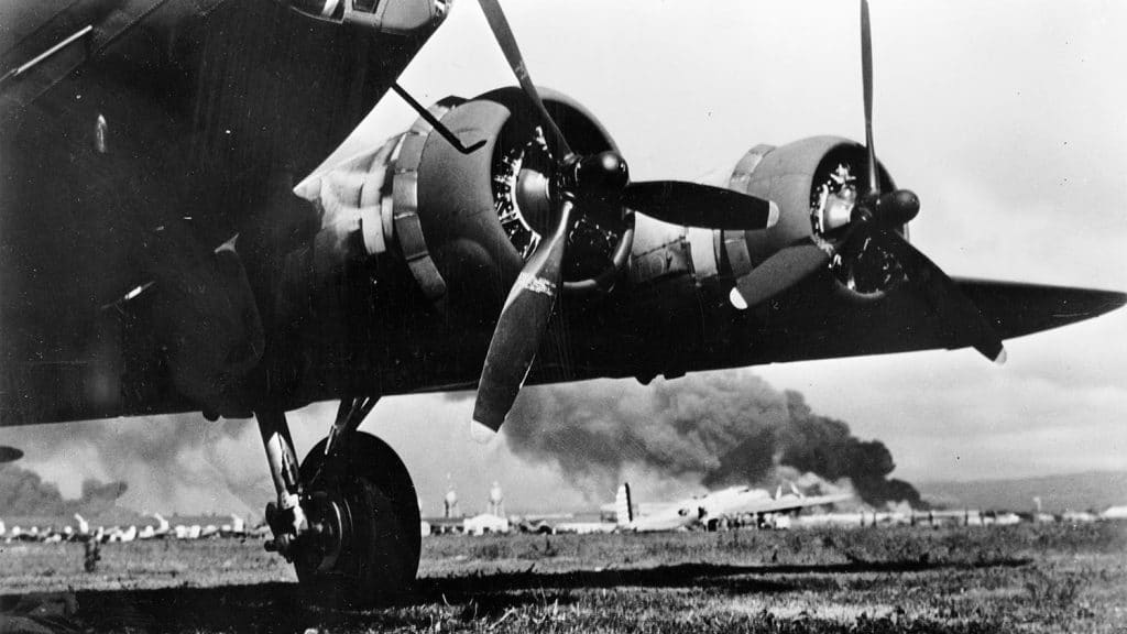 Hickam Field during the Japanese attack. A camouflaged Boeing B-17E Flying Fortress is in the foreground, a silver B-17D is visible in the background. Photo: Library of Congress.