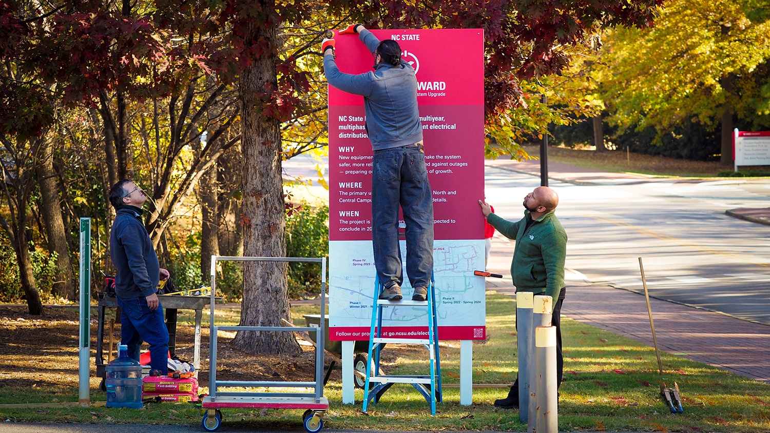 Facilities Division staffers install Power Forward informational signs around campus.