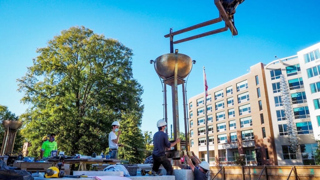 Workers install one of the four bronze torchieres surrounding the belltower. 