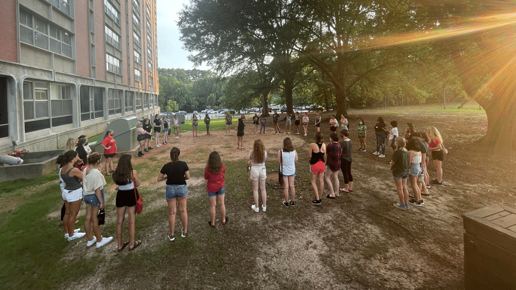 A group of students stand outside in a circle.