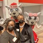 Two alums post with the NC State mascot, Mr. Wuf