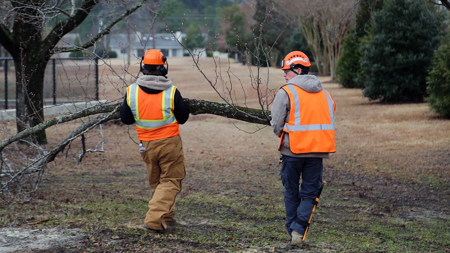 Kelly Blair and a coworker carry a tree limb across a field in Wilmington, North Carolina.