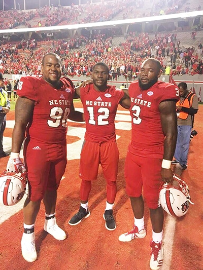 three NC State football players in uniform