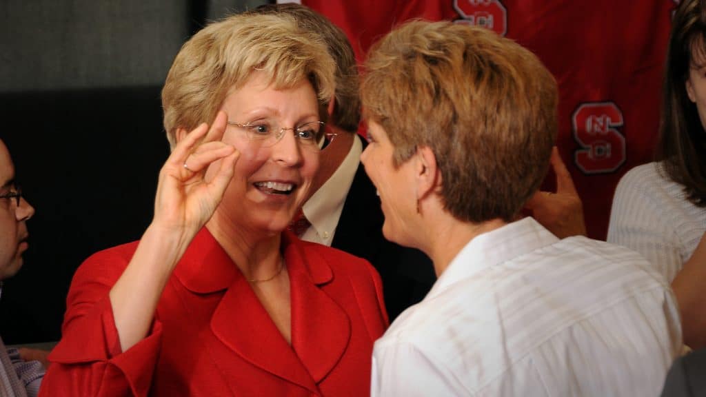 Debbie Yow wears a red blazer and makes wolf hands as she speaks with her sister Susan Yow.