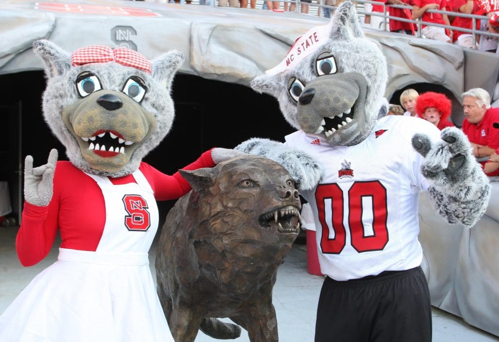 Mr. and Ms. Wuf pose with Fury, a bronze sculpture at the team entrance at Carter-Finley Stadium.