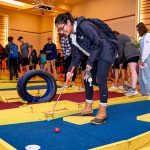 A student plays mini-golf at a Day of Giving student event.