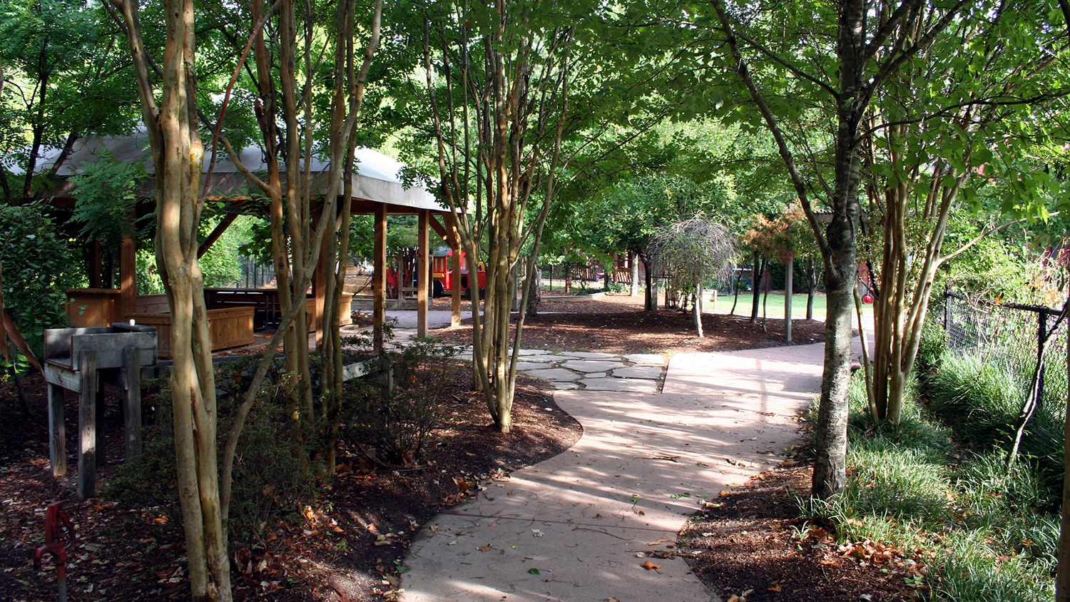 Outdoor play area with path winding through trees at child development center.