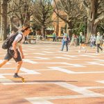 A student skateboards through the Brickyard.