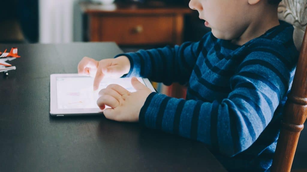 Child on tablet at kitchen table.