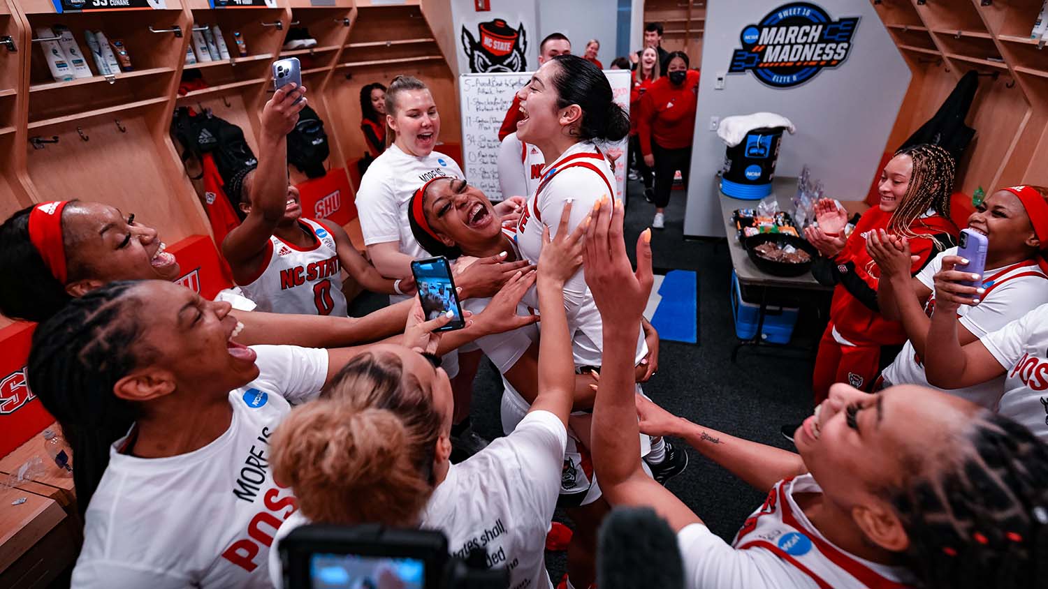 NC State's women's basketball team celebrates in the locker room.