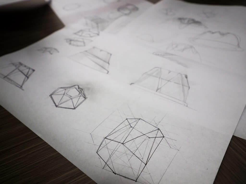 Geometric pencil drawings on white paper show drafts of take-out containers. 
