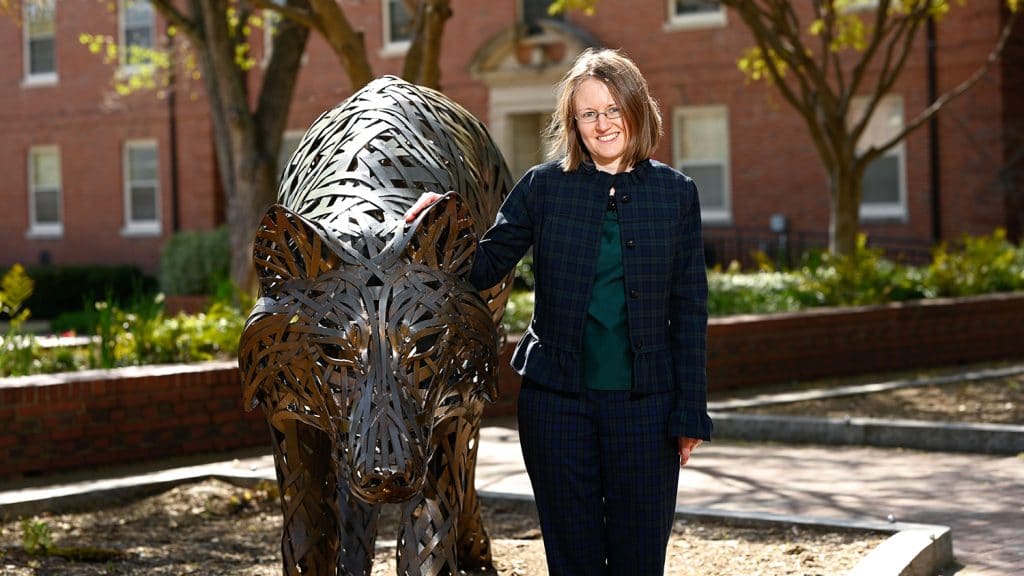 Katie Homar standing with bronze wolf at NC State's Wolf Plaza