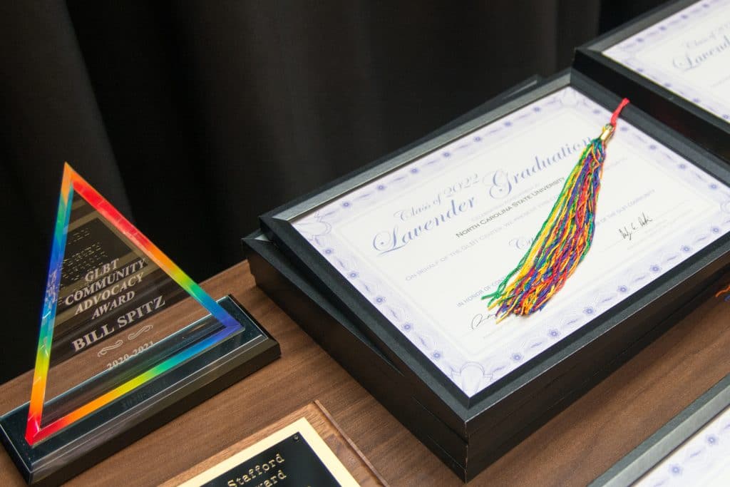 GLBT Center awards and certificates are displayed on the table with a rainbow pom pom.