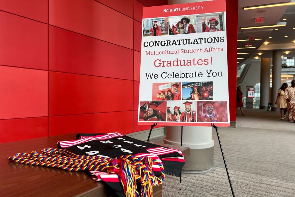 Welcome display at the Multicultural Graduation features a photo board and MSA regalia on the check in table. 