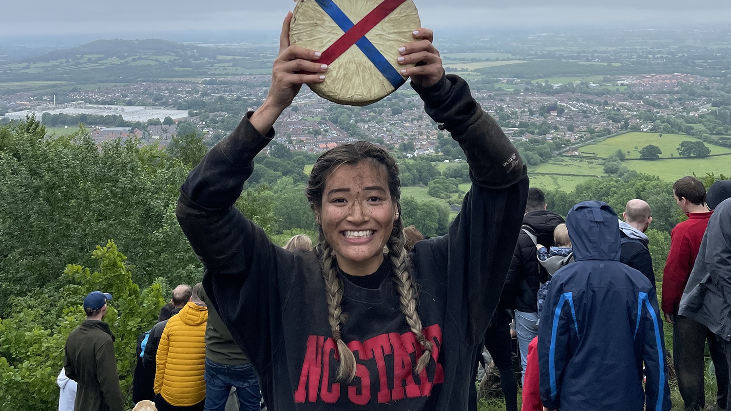 Abby Lampe holding a wheel of cheese over her head.