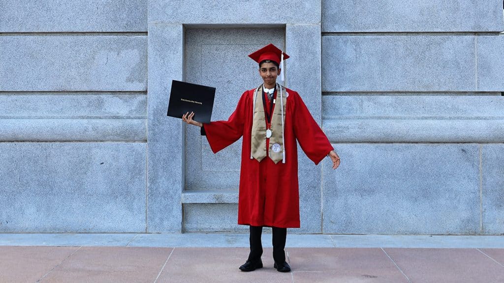 Madhusudan Madhavan holds his diploma at the base of the Belltower.