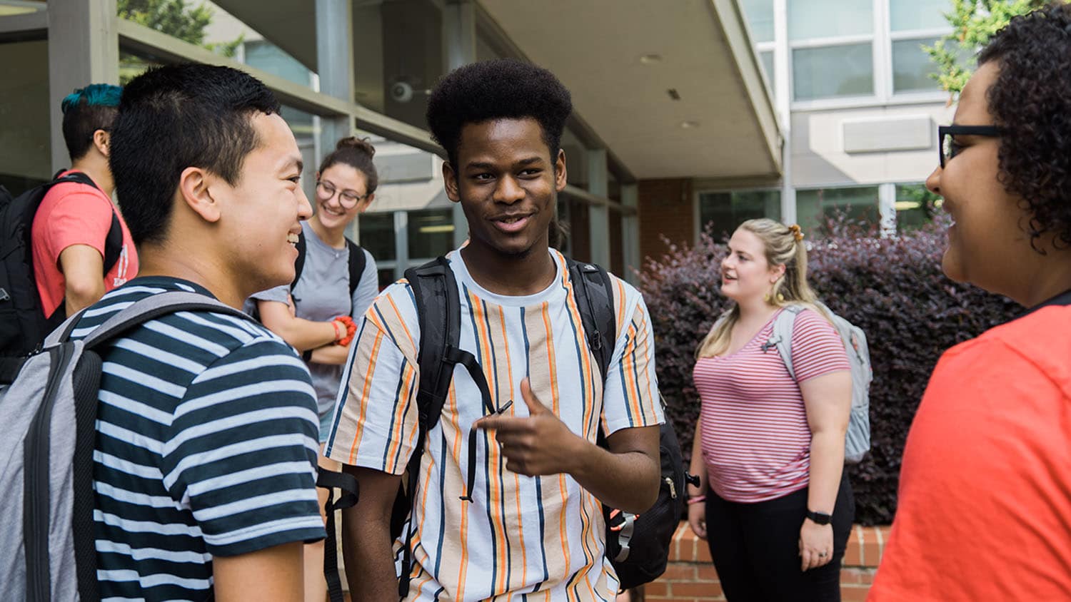 A group of students talks outside of Bragaw Hall.