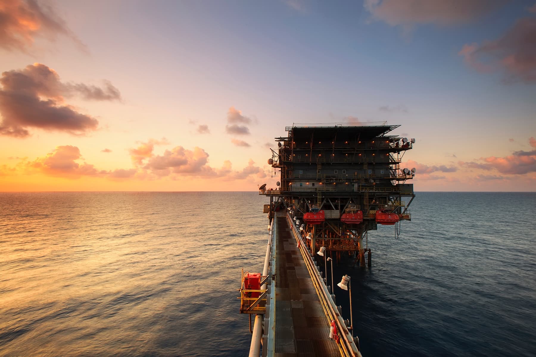 A photograph shows an oil rig standing in the middle of the ocean.