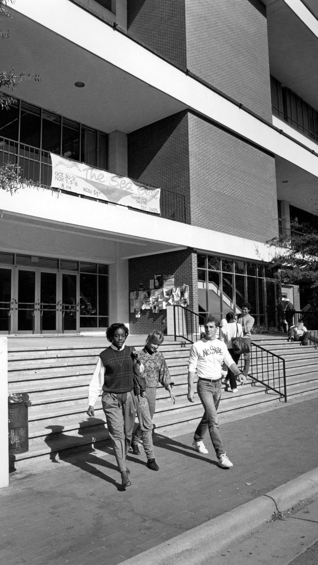 Black and white archival photo of three students walking out of the University Student Center.