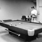 Students play pool at a table in the student center in this black and white archival photo.