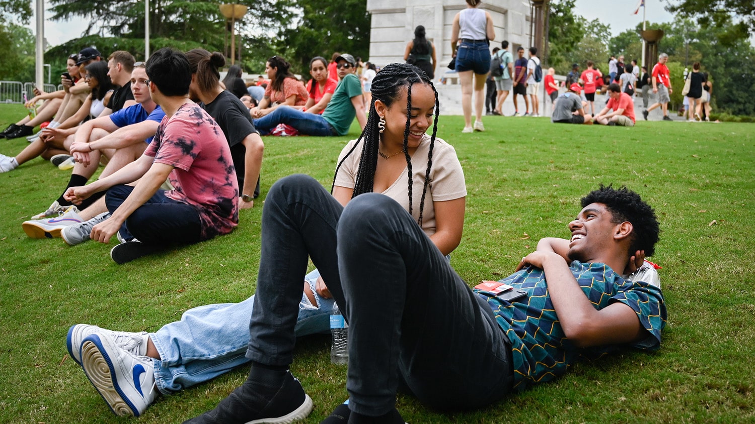 At the base of the Belltower, groups of students lounge in the green grass.