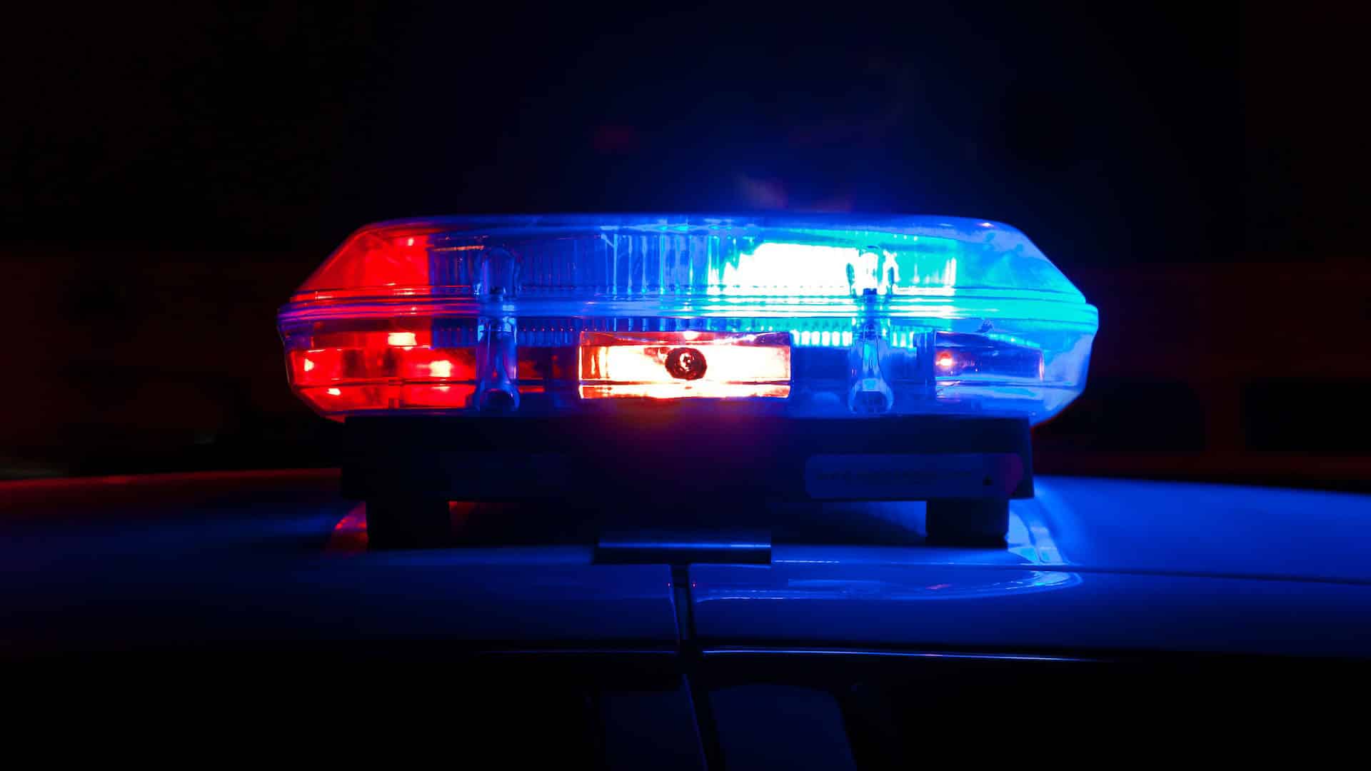 a red and blue siren light shines on the roof of a car