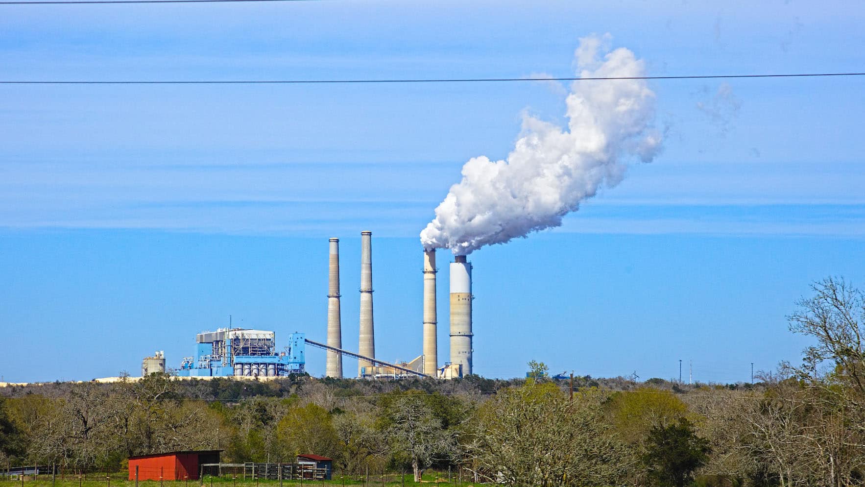 a coal-fired power plant in Texas releases a white cloud against a blue sky