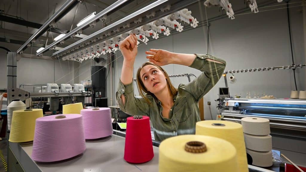 Student working with spools of thread.