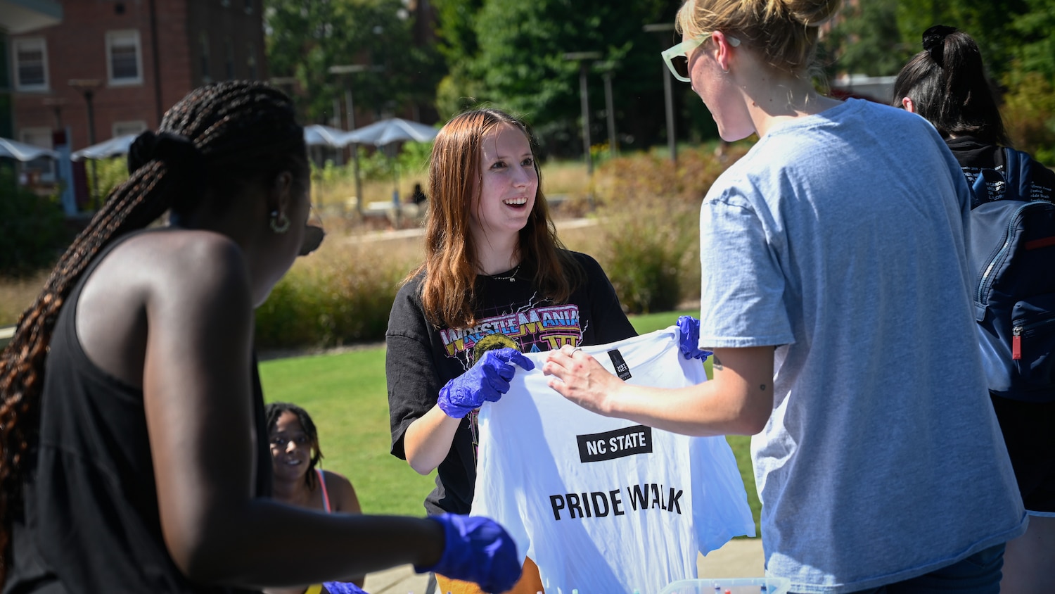 Student holding up a Pride Walk T-shirt before tie-dying it