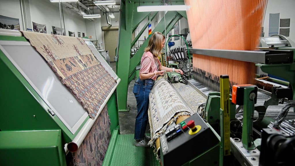 Student standing on a loom.