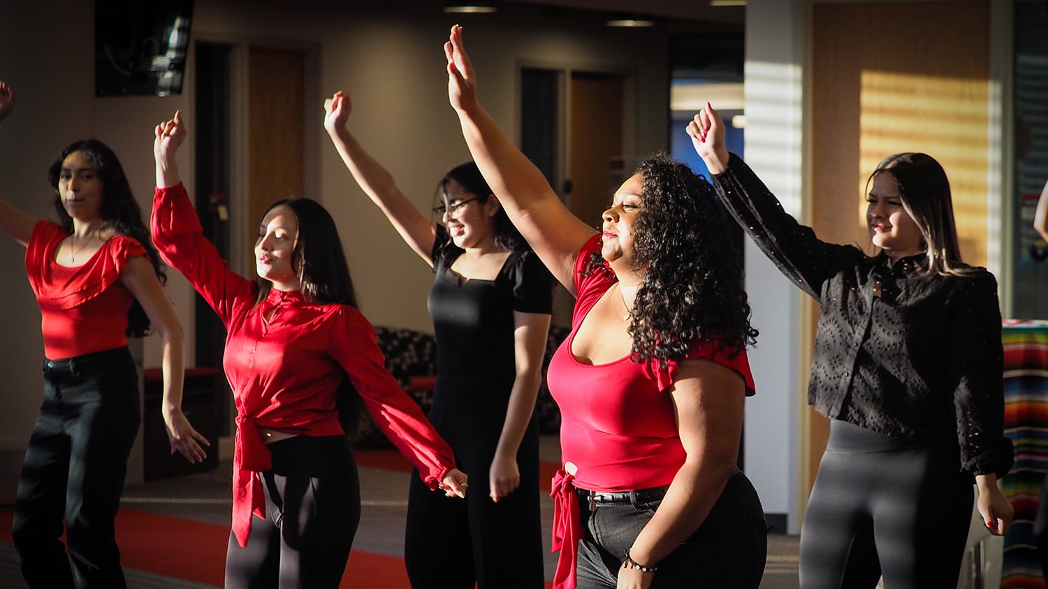 NC State student dancers in red and black raise their hands at a 2022 event celebrating Latinx Heritage Month.