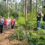 Forest manager and student work crew member address a community tour in the forest.