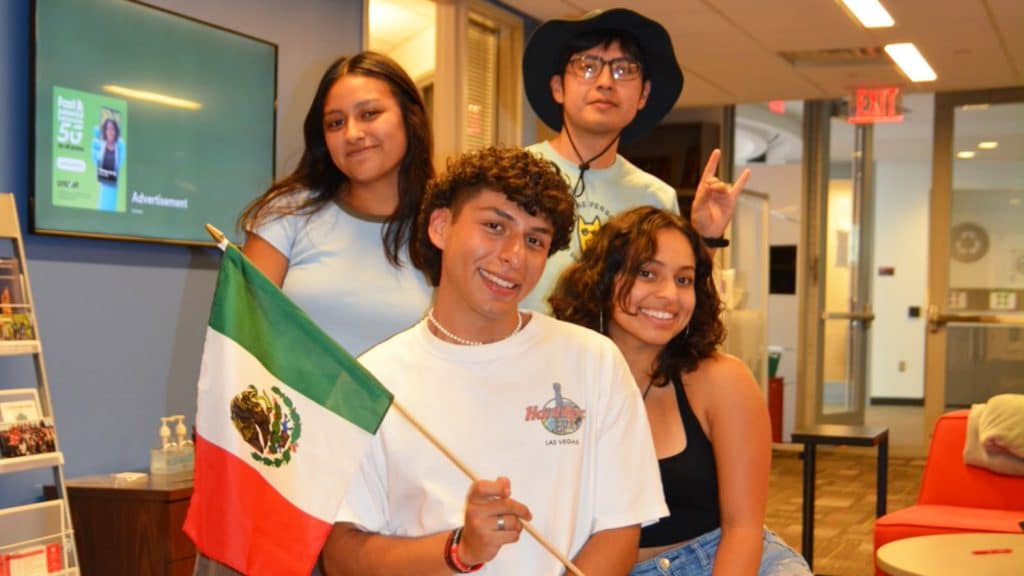 A group of students pose with a Mexican flag at the MSA suite in Talley Student Union.