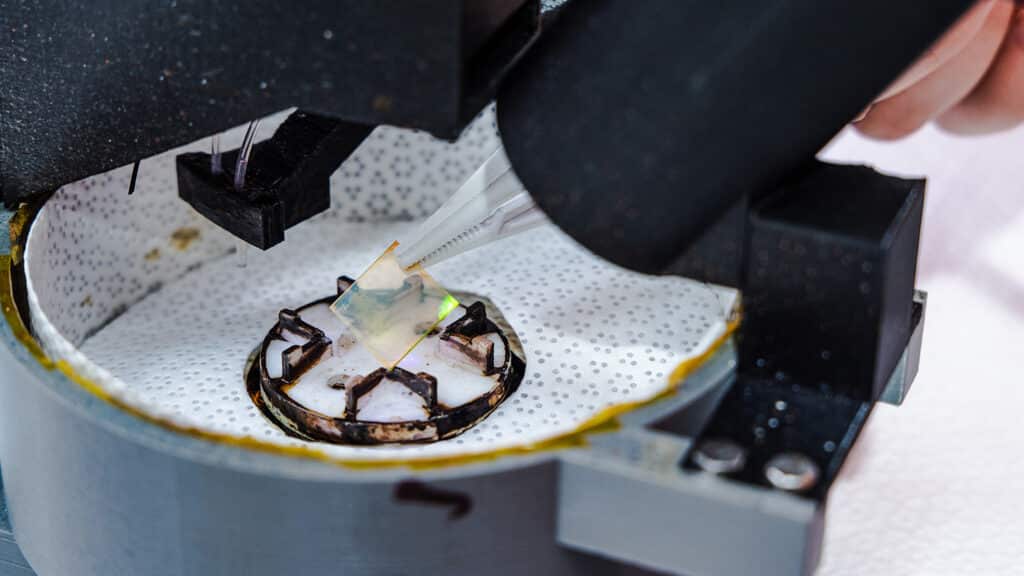 Tweezers grasp a microscope slide that has been in a machine. 