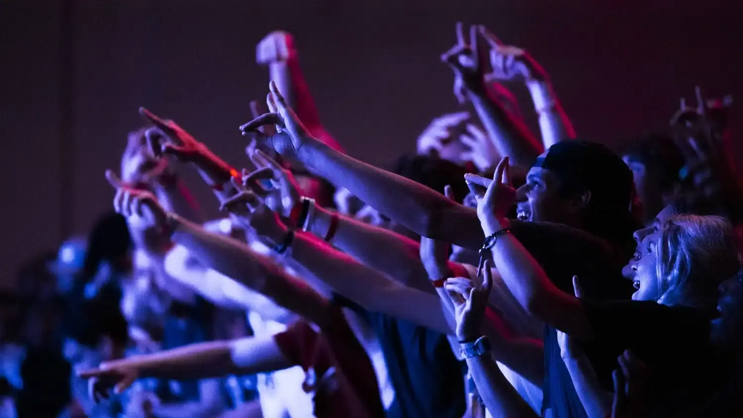A crowd of students raise their wolfies during a performance at PackHowl.