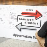A student signs a large banner that says "NC State Transfer Student Appreciation Week."