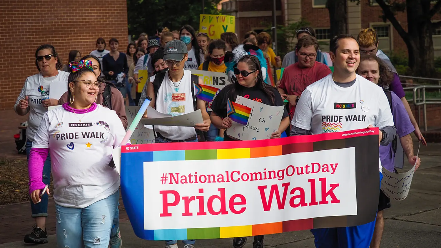 A crowd of students, staff and community members parade through campus during the Pride Walk event.