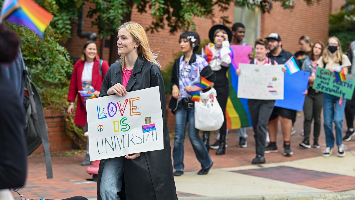 Community member holds up a sign during the Pride Walk around campus.