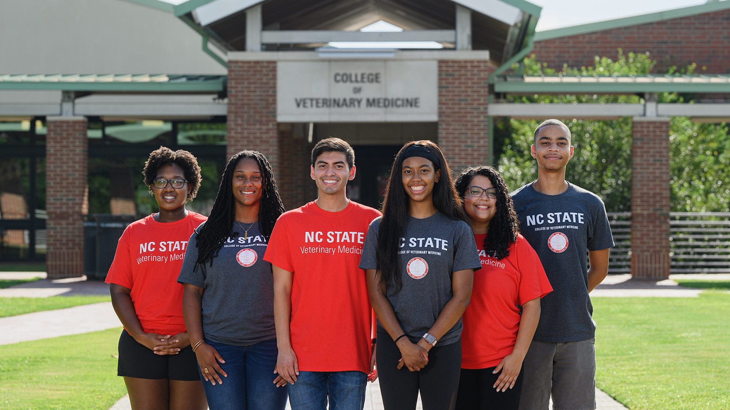 A group of racially diverse students stand in front of the College of Veterinary Medicine.