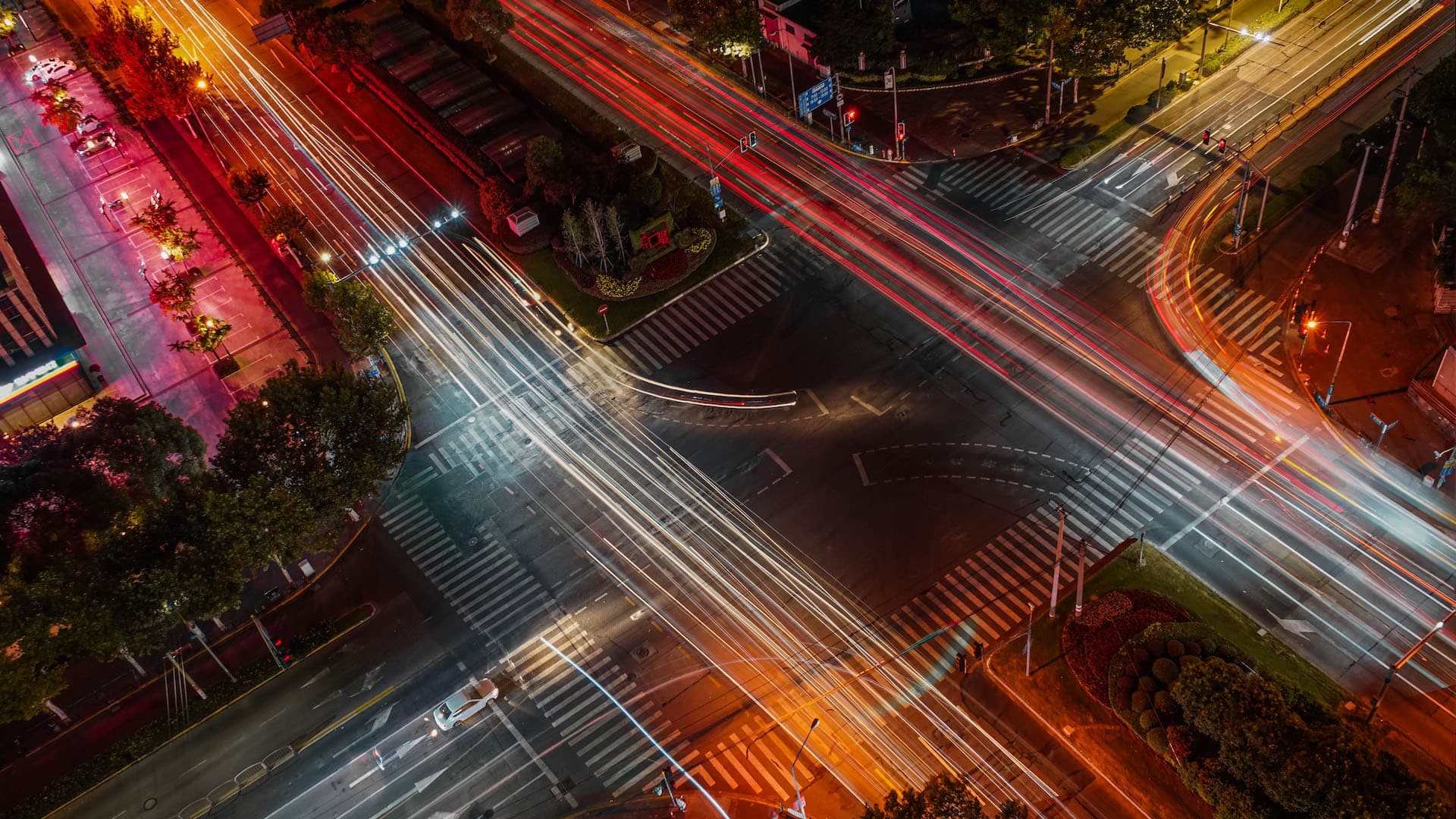 time-lapse image shows cars moving through an intersection at night