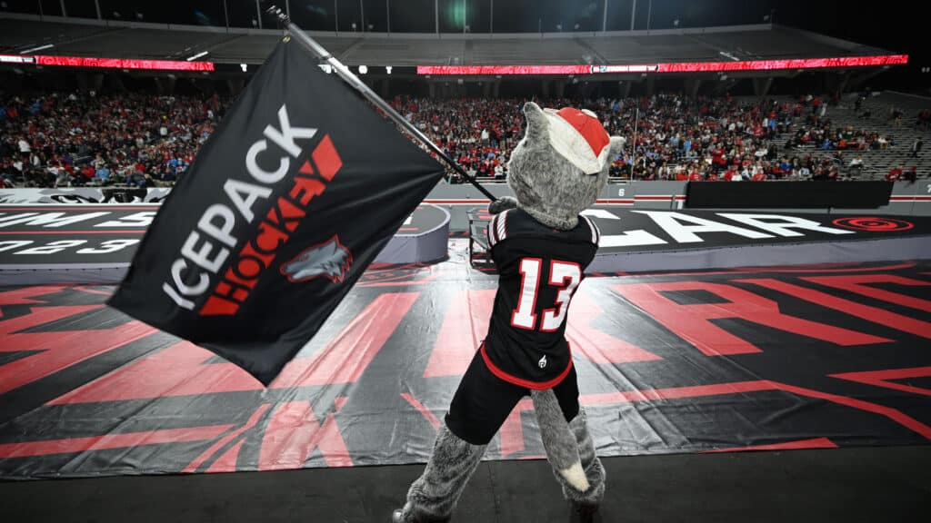 Mr. Wuf waves an Icepack Hockey flag at Carter-Finley Stadium.