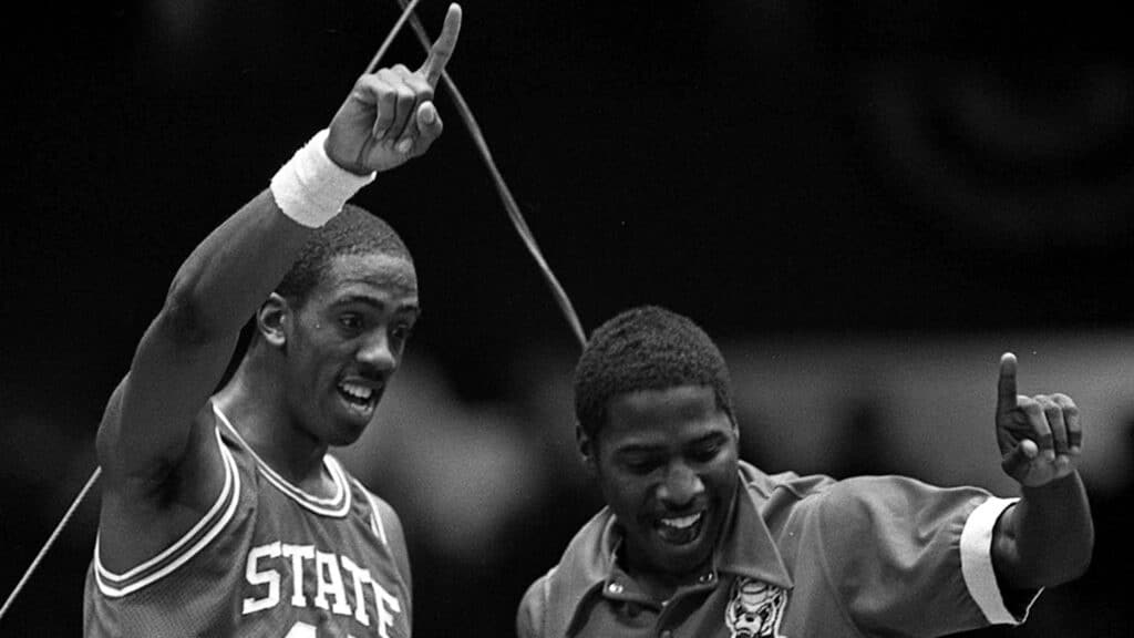 Black and white image of Cozell McQueen and Ernie Myers from their perch atop the backboard after NC State's 1983 NCAA Champship victory. 