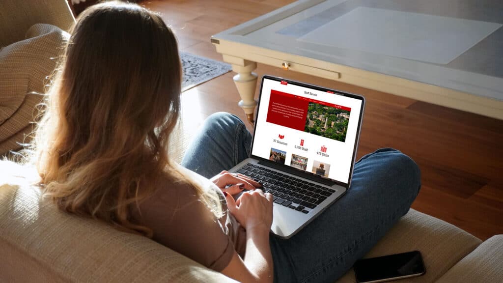 Women sitting on a couch looking at her laptop.