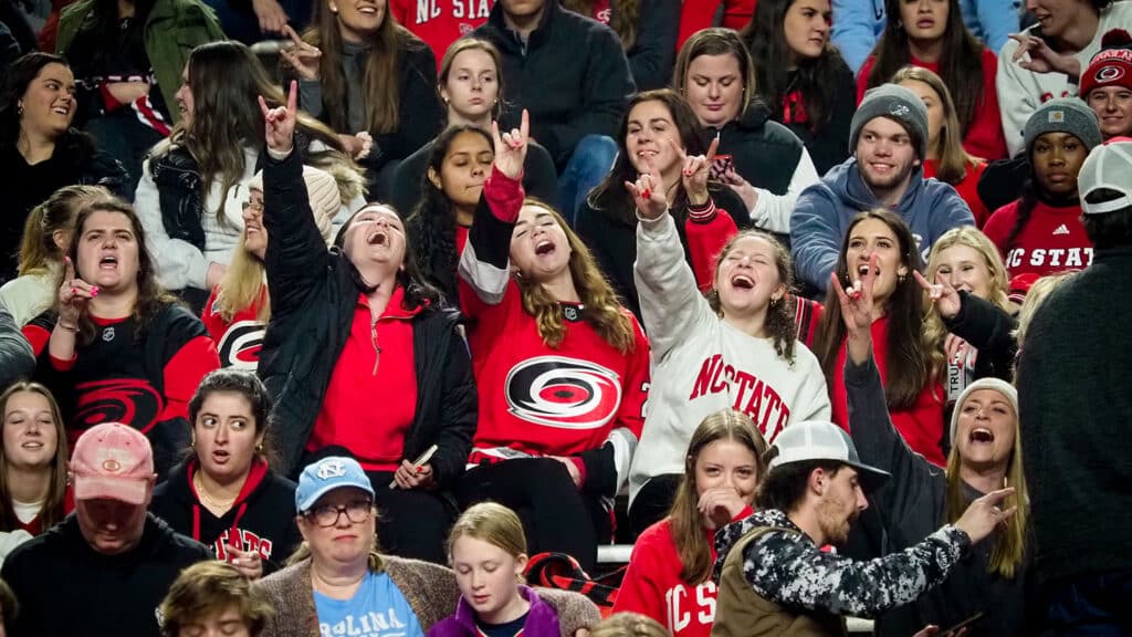 NC State Icepack hockey fans throw up wolf hands at Carter-Finley Stadium.