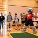 Mr. Wuf celebrates a successful putt while playing mini golf at the 2022 Day of Giving student event