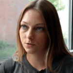 Laurie Capps Bolster speaks with someone off-camera during an interview. The photo shows her face and shoulders. 