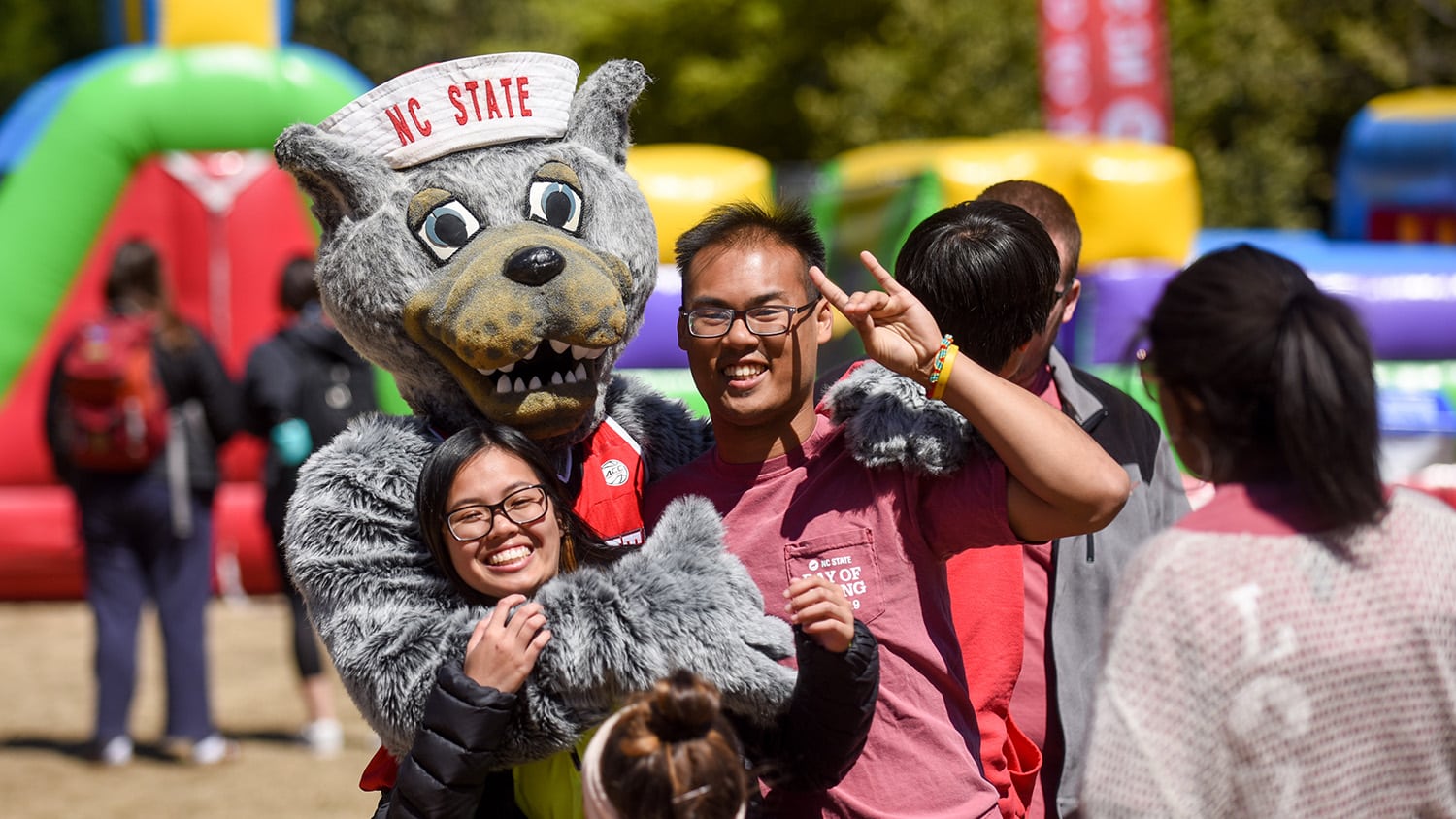 Mr. Wuf hugs two students during the 2019 Day of Giving student event