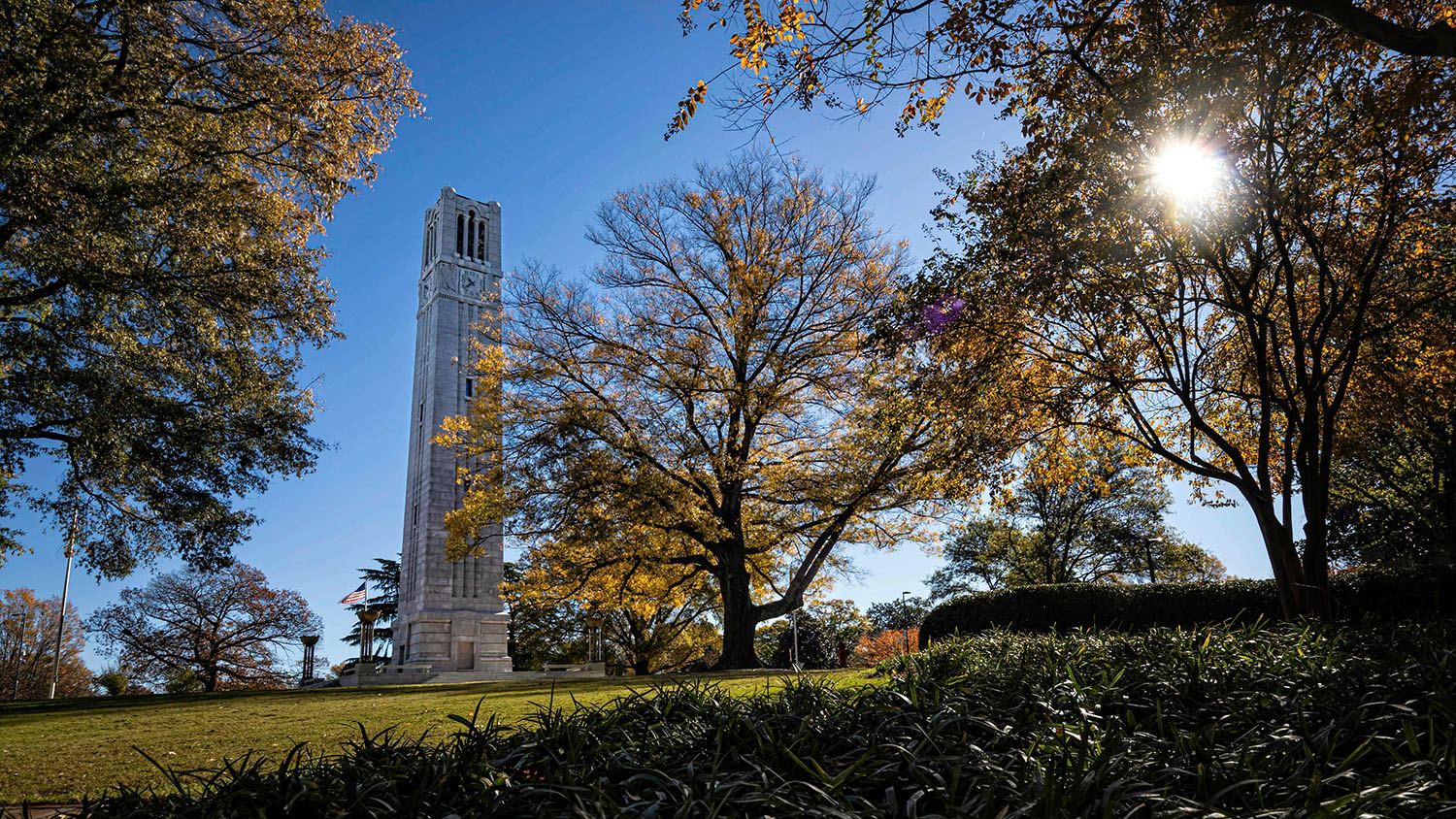 NC State's Memorial Belltower stands proudly amidst a clear and sunny fall day.